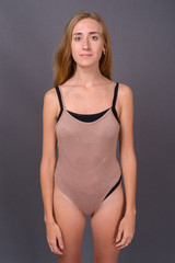 Fototapeta premium Young beautiful woman with blond hair wearing leotard against gr