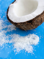Half of coconut and desiccated coconut on blue background