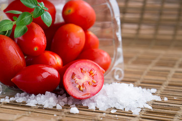 Fresh ripe cherry tomato, sea salt and a small branch of sweet basil on wooden background