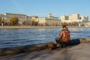         Fisherman catches fish in the river on the city embankment. Hobby Concept
