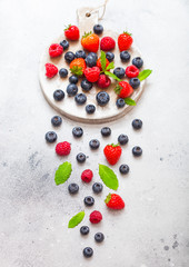 Fresh raw organic berries on round vintage board background.Top view. Strawberry, Raspberry, Blueberry and Mint leaf