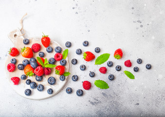 Fresh raw organic berries on round vintage board background.Top view. Strawberry, Raspberry, Blueberry and Mint leaf