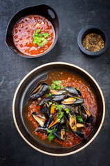 Traditionelle gegrillte italienische Miesmuscheln in Tomaten und Rotwein Sauce dekoriert mit Petersilie als Draufsicht auf einem Modern Design Teller