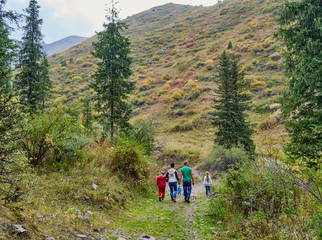 Fototapeta na wymiar family walking along a mountain path deep into the gorge among the trees