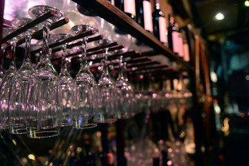 wine glasses stacked on black metal hanging bar glass racks in a bar