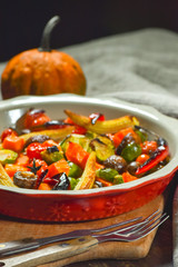 Delicious vegetables baked in the oven on a ceramic plate on a wooden table. Devices, fabric and accessories.