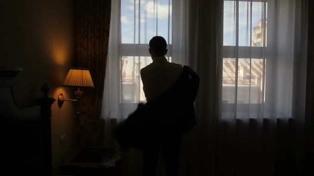 morning groom before the wedding ceremony. Silhouette of a man wearing an elegant jacket