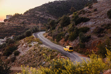 Yellow taxi riding on the mountain road on sunset