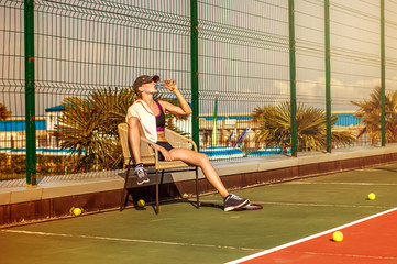 Woman tennis player drinking water from bottle