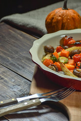 Delicious vegetables baked in the oven on a ceramic plate on a wooden table. Devices, fabric and accessories. Copy space.