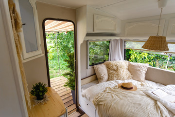 Inside the camper van. Unfilled bed, pillows, guitar, book, hat, white wooden decoration of the...