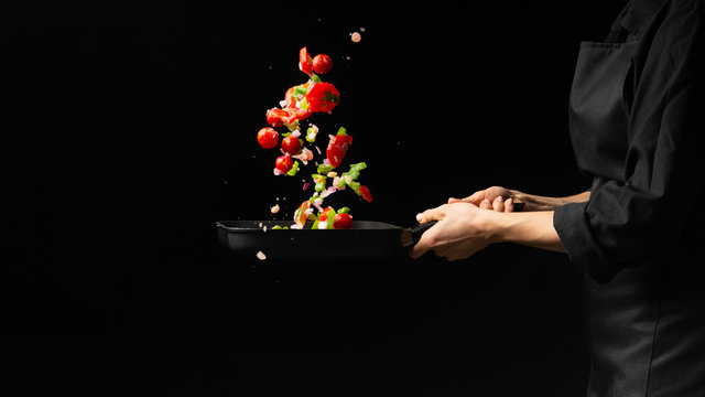 Chef preparing vegetables on a dark background on a grill pan