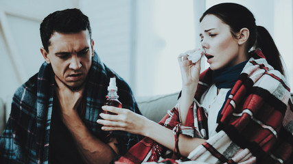 Sick Couple Sitting on Sofa in Checkered Blankets.