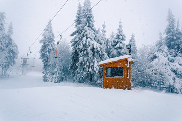 Empty t-bar lift and wooden building at snowfall