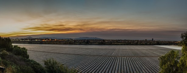 Fototapeta premium Sky over the parrallel lines of the agriculture fields glows as dawn begins to illuminate the distant mountain ridges.
