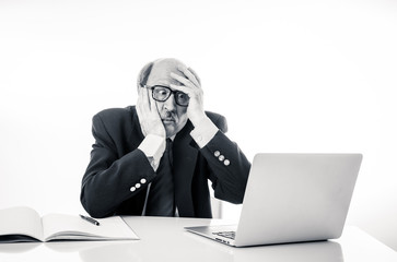 Overwhelmed and tired old businessman working with laptop feeling angry at office