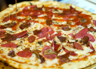 close-up of sausage, bacon, ham, yellow cheese and mushroom pizza. On hot pizza spices scattered