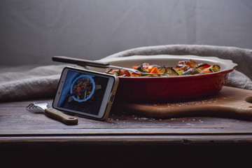 Instagram photography blogging workshop concept. phone near a stylish plate with grilled vegatables on wooden rustic background.