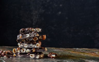 Dark chocolate with nuts. Bright and tasty photo on a dark background. Stone stand with a relief...