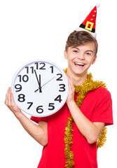 Portrait of smiling teen boy with Christmas hat. Teenager wearing red t-shirt holding big clock. Holiday concept - happy cute child isolated on white background.