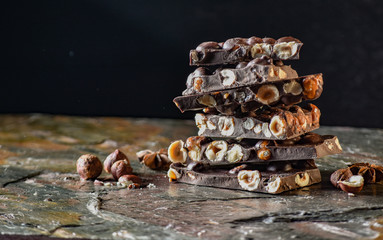 Chocolate tower with cocoa and nuts, chocolate culinary background. Handmade chocolate pieces with spices.