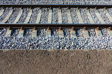 Railroad tracks with concrete sleepers. Detailed image of a railway track with gravel dumping. Side view.