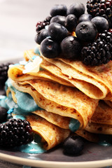 Delicious Tasty Homemade crepes or pancakes with blackberries,blueberries and blue spirulina nicecream.