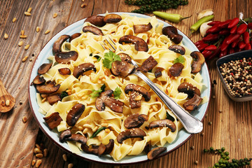 Pasta fettuccine with mushrooms and spinach on rustic background.