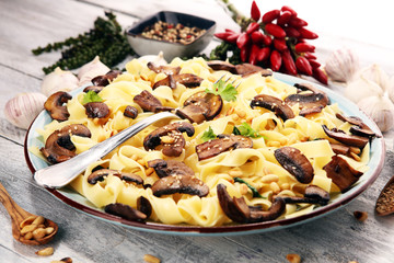 Pasta fettuccine with mushrooms and spinach on rustic background.