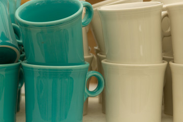 Dark green and beige coffee cups are stacked on top of each other and side by side. They are sitting on a table.