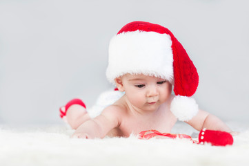 very beautiful bright emotional happy little baby in Santa hat crawling on white plaid