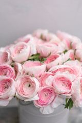 Ranunculus asiaticus or Persian Buttercup. Bunch of pastel pink blossom . Light gray background, metal vase. Wallpaper, flowers texture