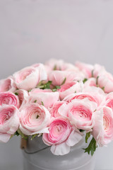 Ranunculus asiaticus or Persian Buttercup. Bunch of pastel pink blossom . Light gray background, metal vase. Wallpaper, flowers texture