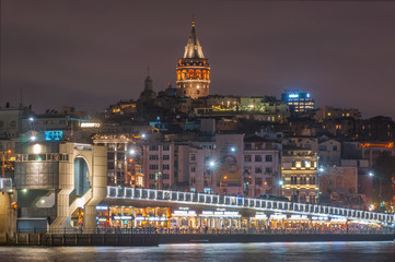 Fototapeta premium Galata Tower and Galata Bridge with lots of fish restaurant at night scene on Golden Horn Eminonu which is famous tourist area Istanbul, Turkey