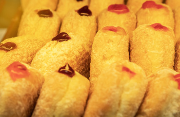 Close up row of sweet golden donuts with jam 