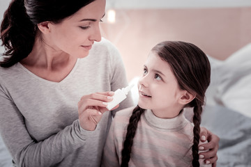 No worries. Close up of positive mother using nasal drops and dripping her daughters nose while...