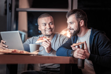 So tasty. Handsome brunette expressing positivity and holding beer while looking at computer