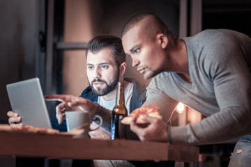 Lets check it. Serious bearded male opening mouth while looking at computer and listening to his partner