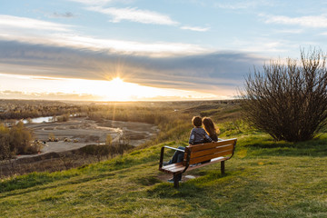 Woman and child sitting on a bench admiring the sunset