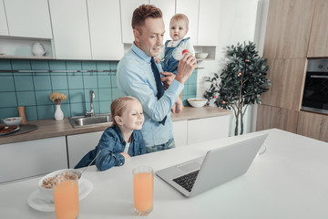 Business and family. Occupied serious attentive father standing in the kitchen near his daughter...