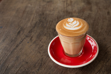 Piccolo Latte art in small glass with red ceramic plate topping beautiful flower art from milk