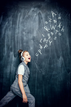 schoolgirl at blackboard in headphones