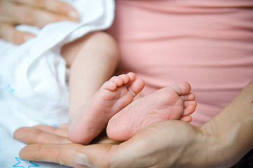 Feet of a newborn girl on her mother's palm