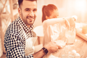 Fototapeta premium Szczęśliwy człowiek z dziewczyną wlewa mąkę w dihses na stole.