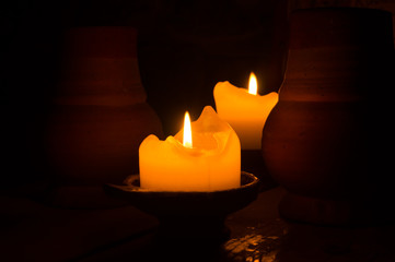 Two burning candles in the dark. clay mug on the table. glowing flame