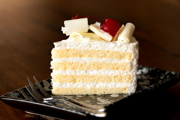 Piece of white cake with vanilla frosting and cherry jelly, topped with white cheese
