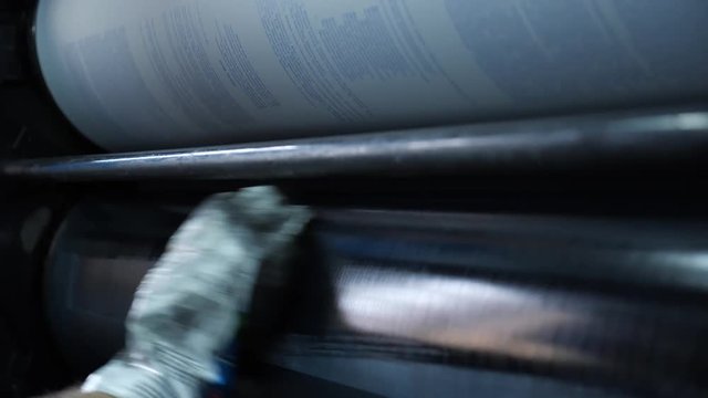 Specialist printer cleans the shaft of the printing press from the old paint cloth. Professional printing machine in the typography.