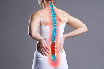 Pain in the spine, woman with backache on gray background, back injury