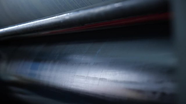 Worker cleans the shaft of the printing press from the old paint cloth. Professional printing machine in the typography.