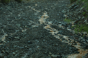 Mountain uneven dirt road with puddles. gray relief